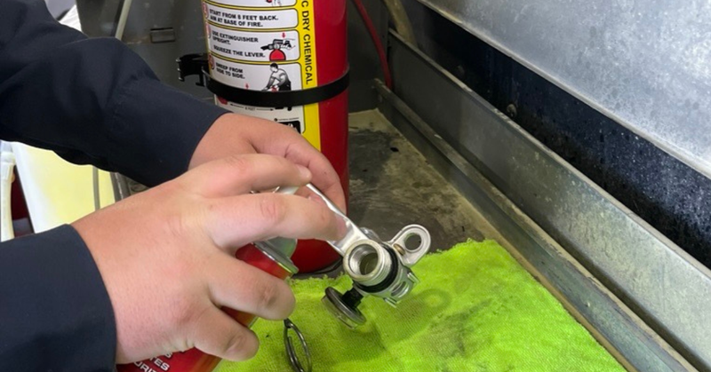 A man working/inspection/refilling a fire extinguisher. 